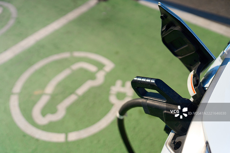 电动汽车插入停车场的充电站 - 可持续性和清洁能源概念图片素材