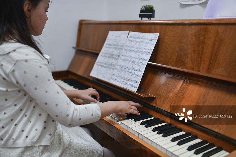 专注的年轻女孩优雅地练习新的钢琴作品，神情专注。图片素材