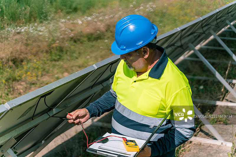 技术员在太阳能发电厂使用万用表检查太阳能电池板图片素材