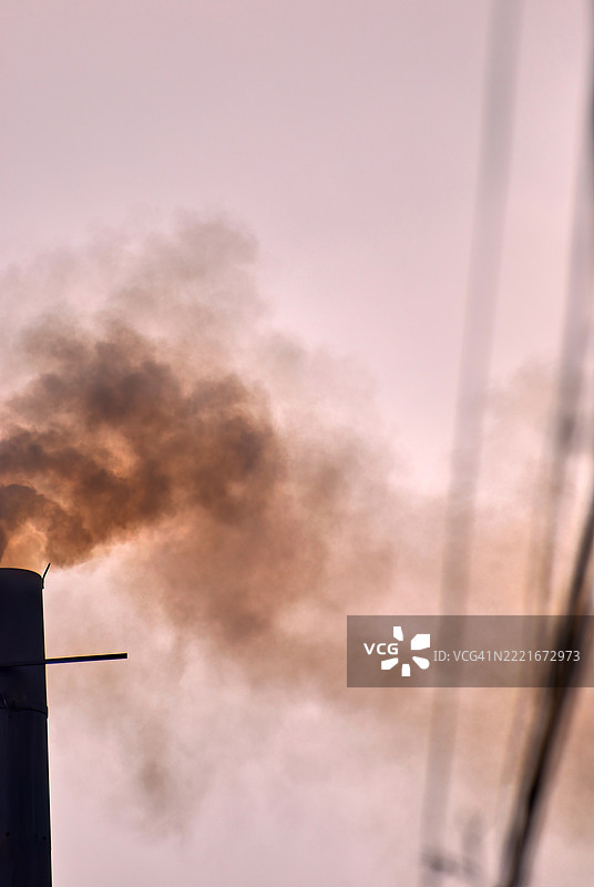 一根黑暗的烟囱或烟道冒出浓厚的黑色烟雾。图片素材