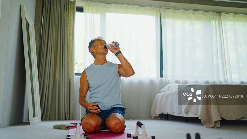 积极的老年男性在家中进行自重训练后喝水图片素材