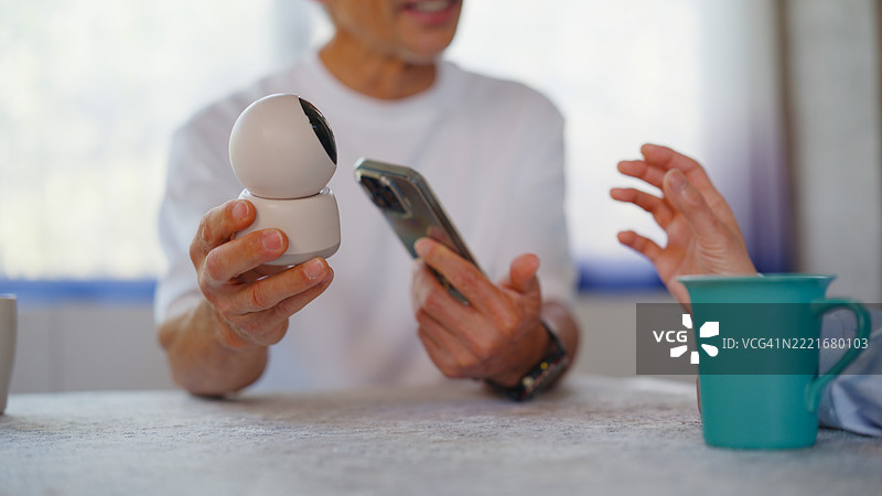 老年夫妇在客厅里安装无线监控摄像头的特写镜头图片素材