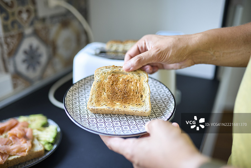 在厨房用电烤面包机烤面包的人图片素材