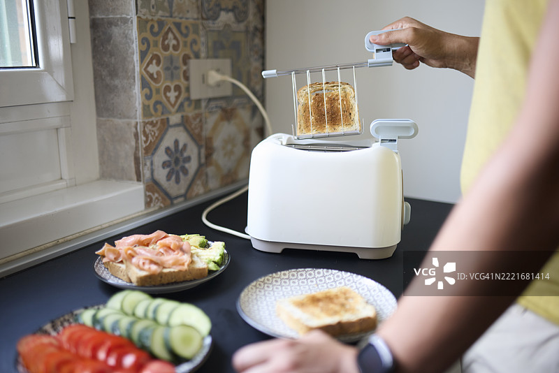 在厨房用电烤面包机烤面包的人图片素材