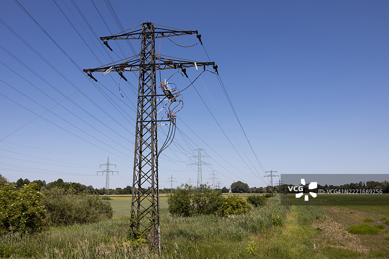 一根生锈的旧电塔和许多现代电塔在背景中。图片素材