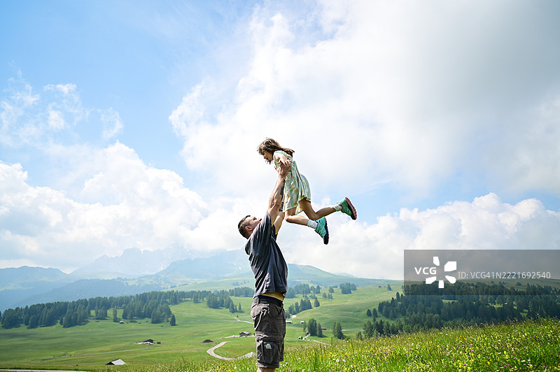 父亲在山景中将女儿举起在空中图片素材
