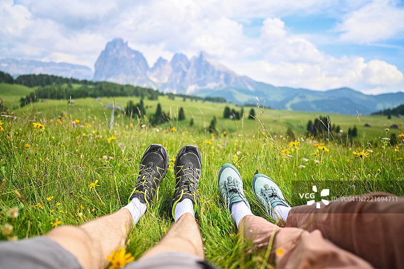 一对情侣躺在草地上，享受山景。图片素材