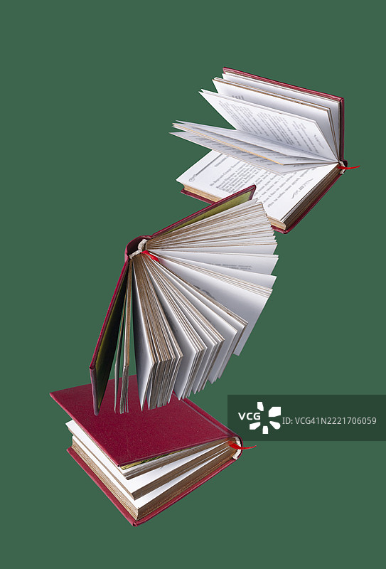 红色封面的书籍在绿色背景上飞舞图片素材