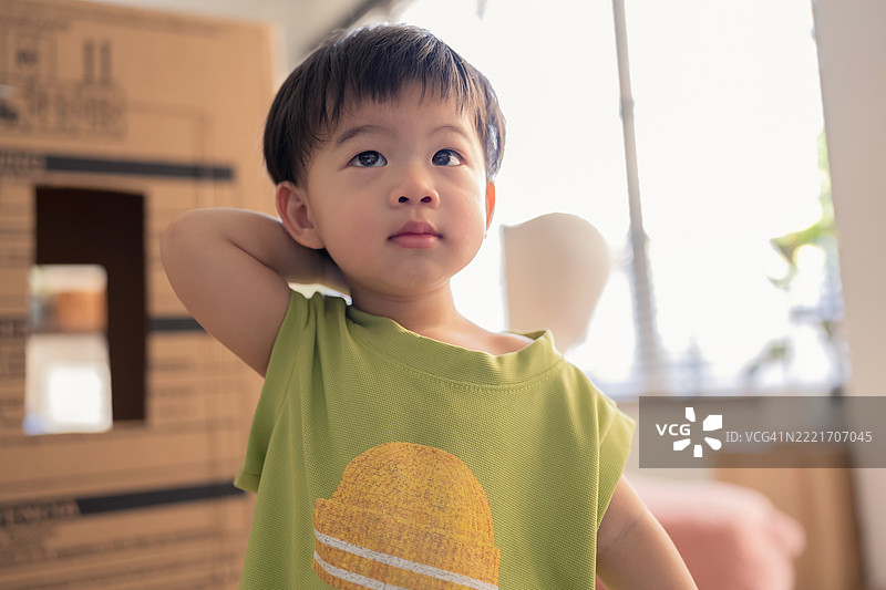 好奇可爱的小亚洲男孩在家里的厨房里顽皮地走来走去，他试图观察家具，脸上洋溢着快乐的微笑，展现出家庭生活的乐趣。图片素材