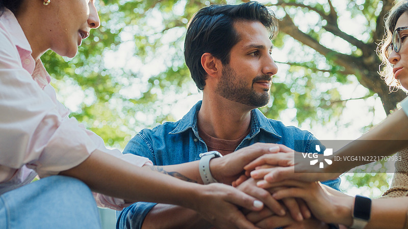 特写镜头，来自不同背景的人们在公园中参与支持性团体治疗会议，分享个人故事和建议，以促进心理健康和康复。心理健康社区概念。图片素材
