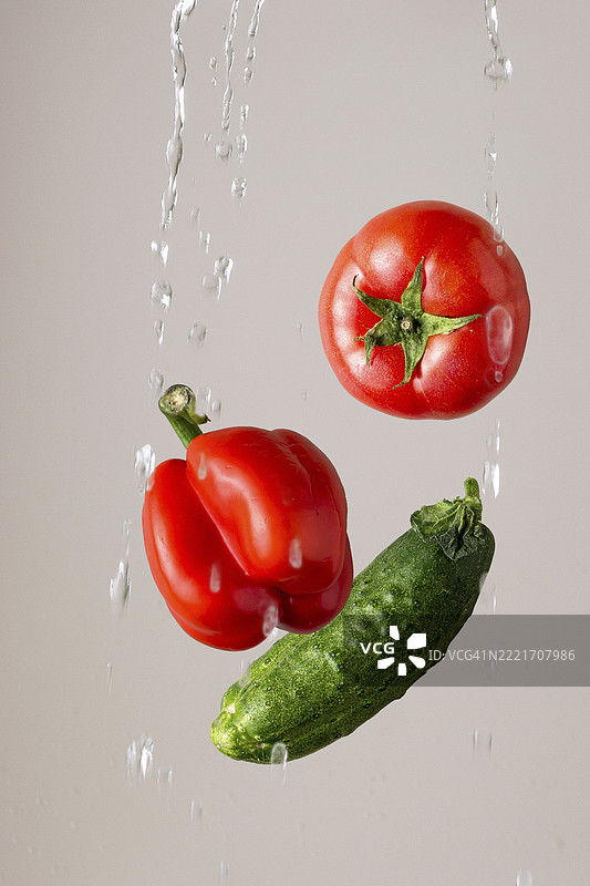西红柿、辣椒、黄瓜在浅色背景下的水花中图片素材