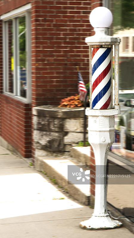 一根色彩斑斓的理发店招牌柱矗立在伯克希尔的李镇理发店前。图片素材