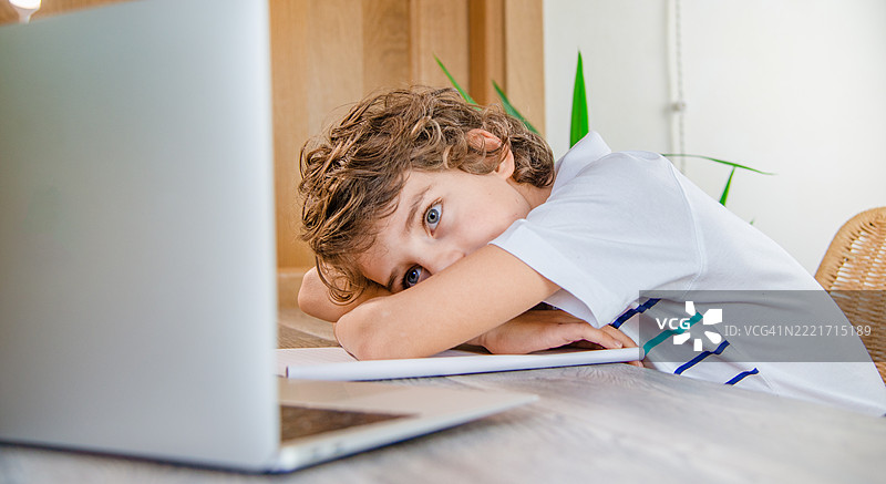 疲惫的孩子在家在线学习时靠在桌子上图片素材
