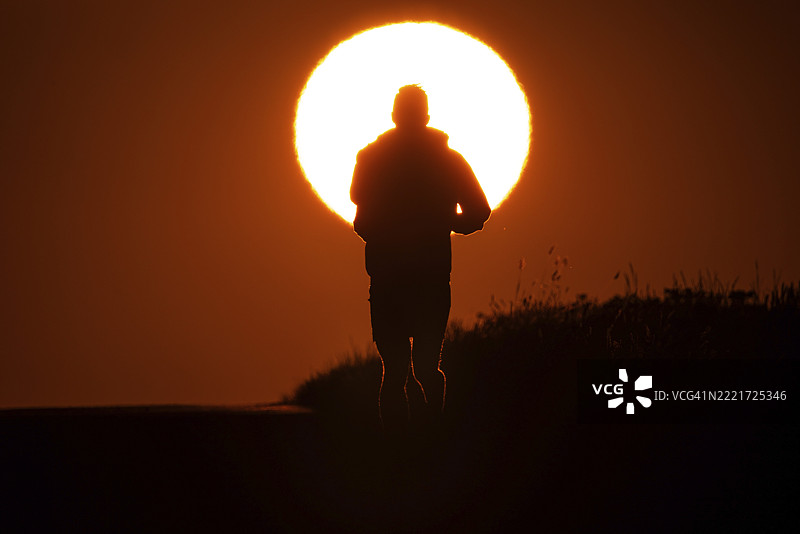 一名慢跑者在德国黑森州法兰克福附近的乡间小路上迎着日出奔跑图片素材