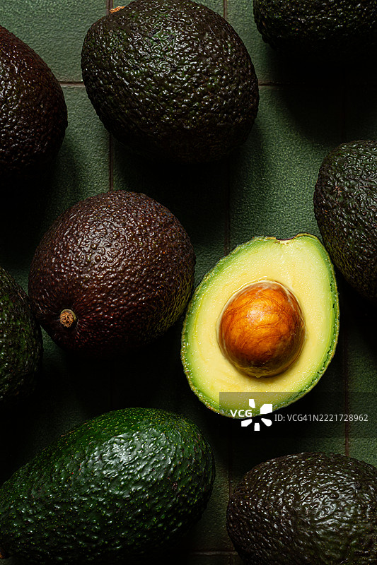 成熟的鳄梨在深绿色背景上。图片素材