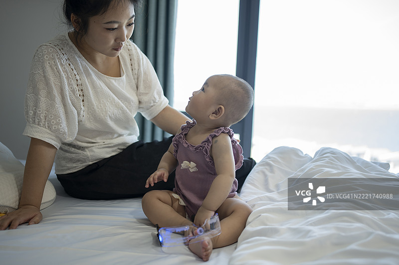 妈妈和她的宝宝在床上快乐地互动，互相凝视。图片素材