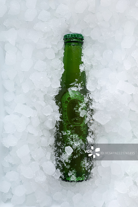 绿色啤酒瓶埋在一堆冰块中图片素材