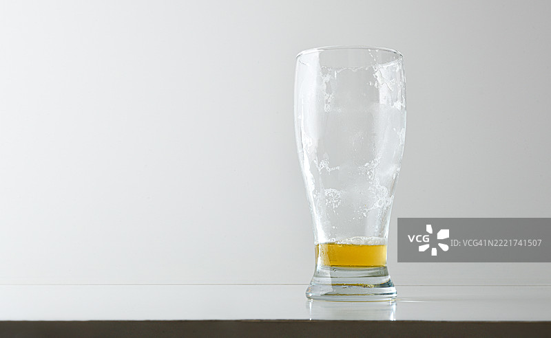空的脏啤酒杯，上面有泡沫，孤零零地放在桌子上图片素材