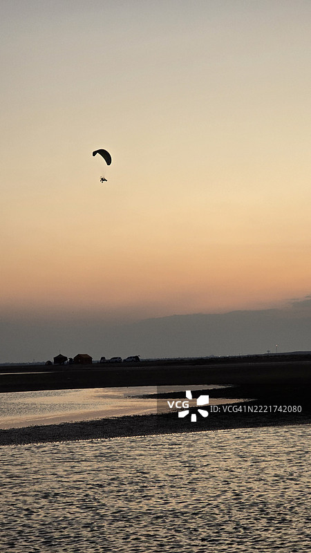 日落时分，海面上滑翔的男子剪影与天空相映成趣图片素材