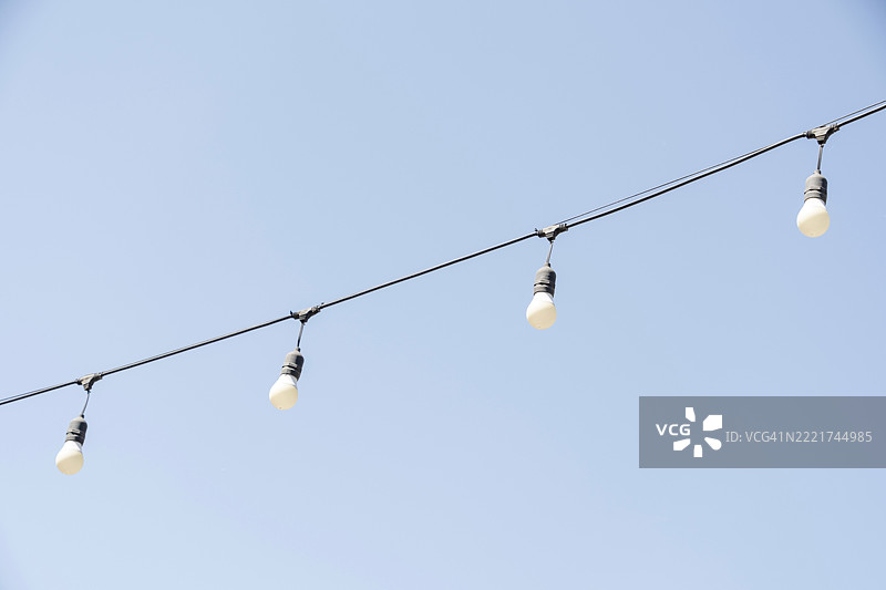 蓝天背景下的电灯泡电线，留白空间图片素材