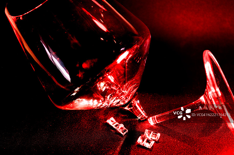 破碎的玻璃碎片，红色光照和抽象图像《强烈红色背景上的破碎玻璃杯：戏剧与脆弱》图片素材