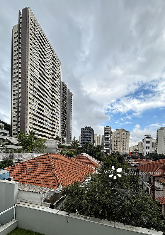圣保罗的景观，前景是各种风格的建筑和一些半独立住宅的瓦屋顶，周围有许多植物。图片素材