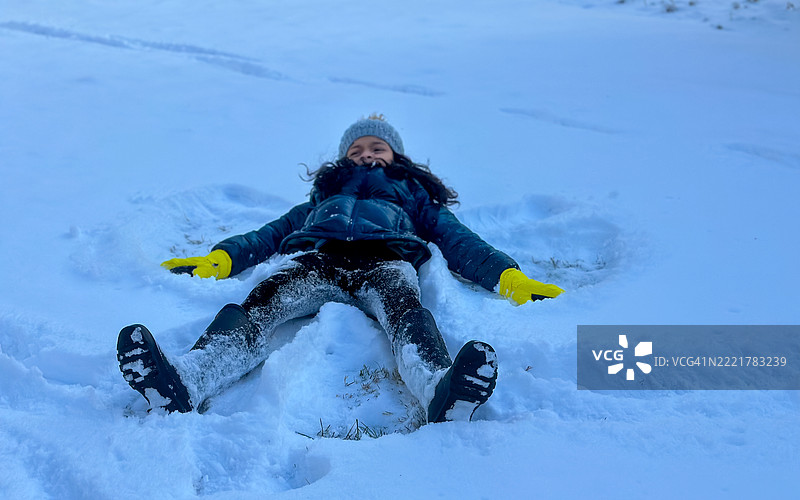 年轻的多种族女孩在雪地里做雪天使图片素材