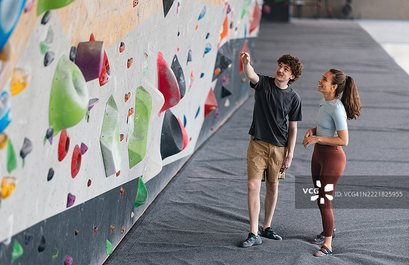 两个朋友在室内攀岩馆规划攀岩路线图片素材