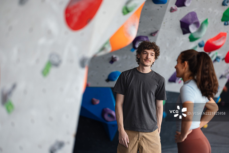 两个朋友在色彩斑斓的室内攀岩馆交谈图片素材