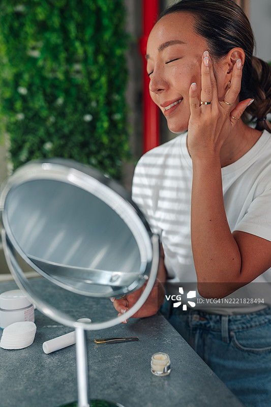 年轻女性在镜子前涂抹面霜图片素材