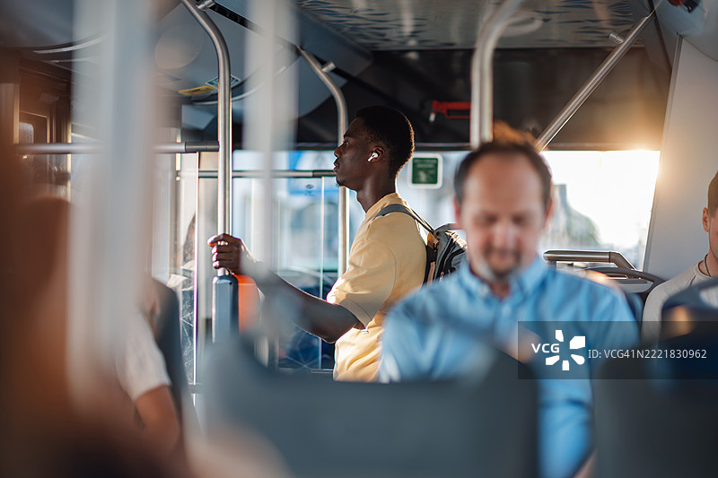 年轻男子乘坐公交车，戴着无线耳机听音乐图片素材