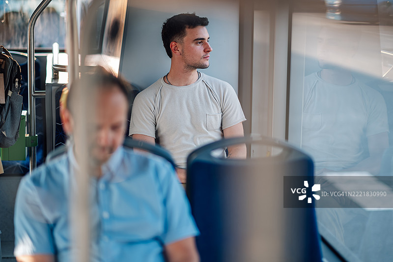 年轻男子在公交车上望向窗外图片素材