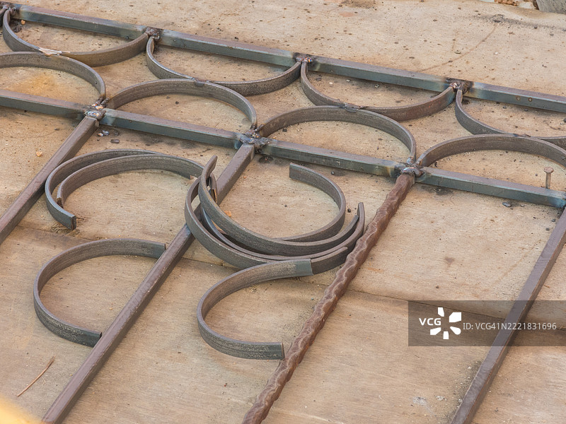 一位铁匠正在弯曲铁壳，以便将它们焊接在一起，形成一个铁栅栏。接下来是美丽的。图片素材