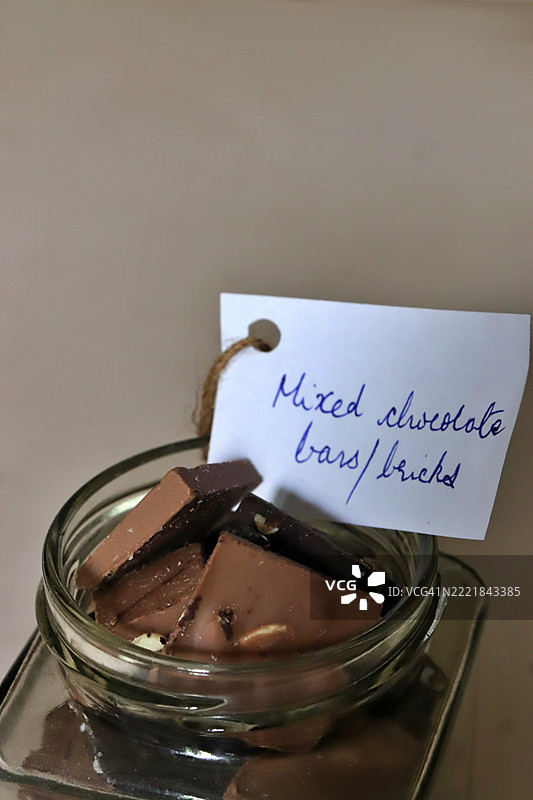 混合巧克力棒特写，装在玻璃罐中，带有手写标签 - 静物摄影图片素材