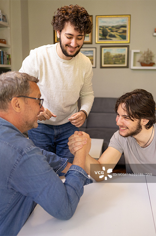 成年儿子与成熟父亲在家中友好的摔跤比赛图片素材