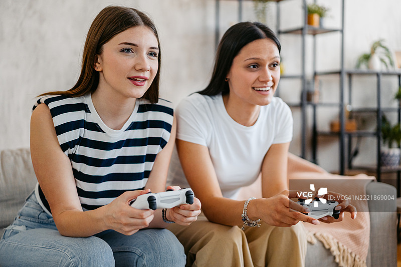 两个女性朋友在客厅用摇杆玩视频游戏图片素材