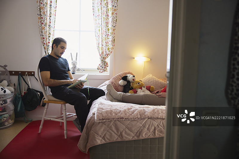 男护士在养老院的卧室里给病人读图画书图片素材