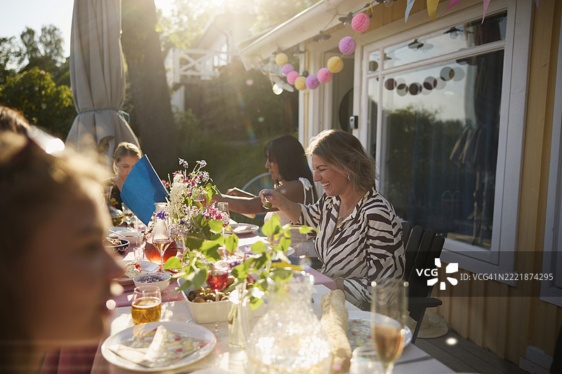 快乐的短发女性在后院的餐桌上吃饭图片素材