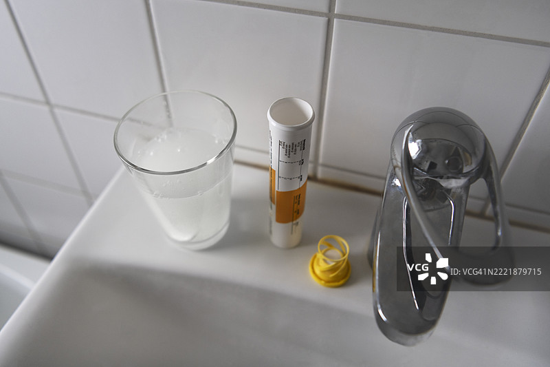 高角度视图的空药瓶与放在水槽旁的玻璃杯图片素材