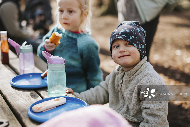 微笑男孩坐在桌旁，面前放着一盘食物图片素材