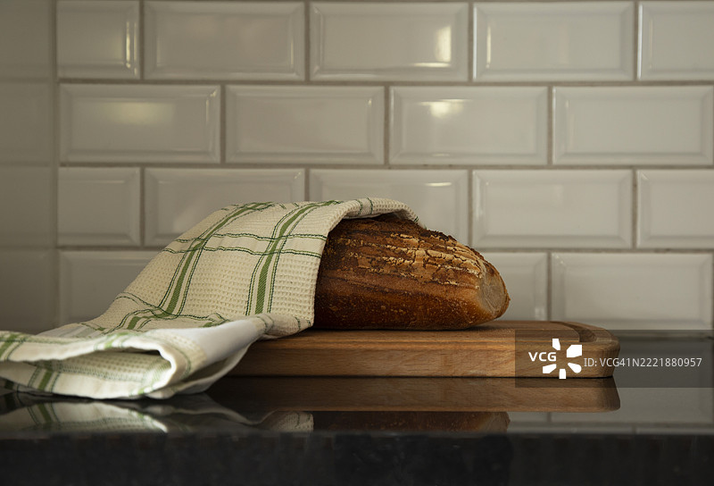 厨房里，铺着餐巾的烤面包放在瓷砖墙边。图片素材