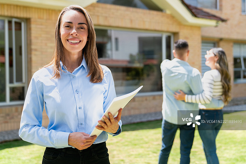 快乐的房地产经纪人向一对夫妇展示房子图片素材