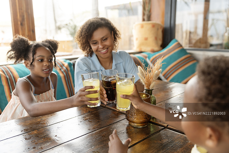 多元化的母亲、女儿和儿子在海滩上享受春日的冷饮图片素材