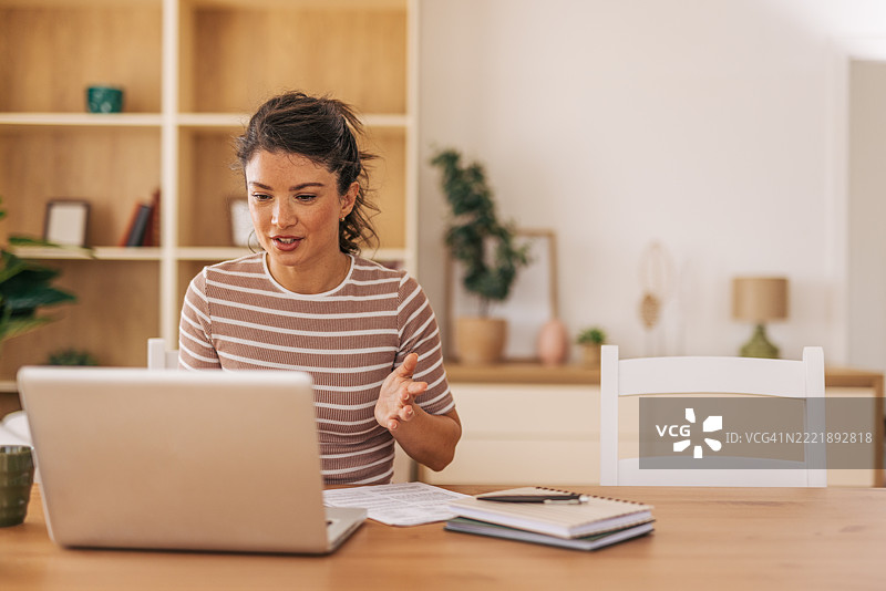 年轻女性在家工作，通过笔记本电脑进行视频通话图片素材