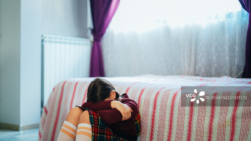 伤心的少女独自坐在卧室地板上图片素材