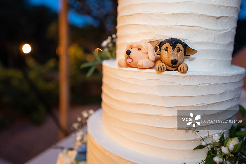优雅的婚礼蛋糕上有顽皮的小狗雕像在浪漫的派对庆祝中偷偷溜进来图片素材