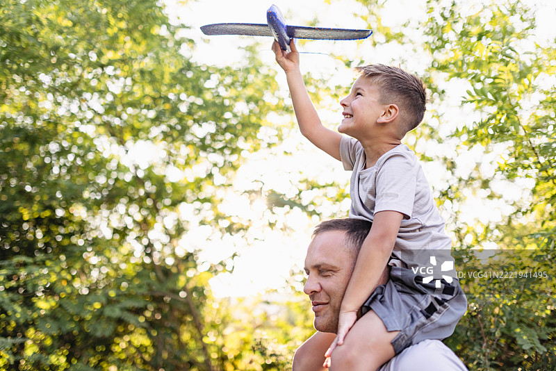 父亲和儿子在阳光明媚的公园里玩玩具飞机图片素材