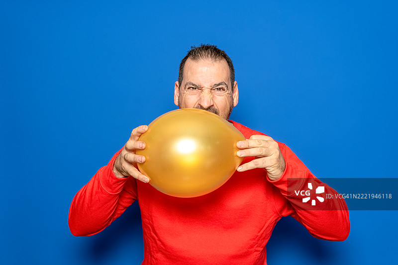 一位四十多岁的有胡子的西班牙裔男子穿着红色毛衣，手里拿着一个……图片素材
