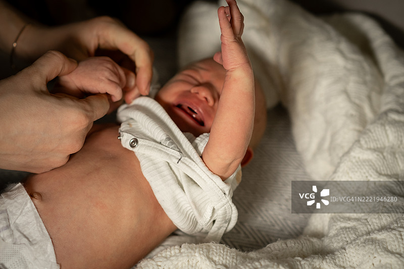 妈妈在温馨的育儿室里为宝宝进行深夜换尿布，环境舒适柔和。图片素材