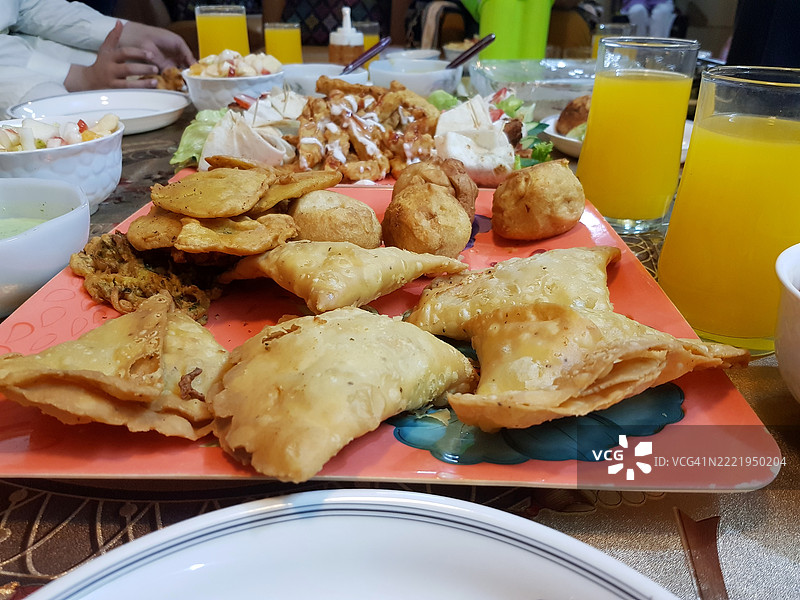 多种亚洲炸食品和油条与橙汁一起在家中餐桌上享用，适合在斋月的开斋时刻。图片素材